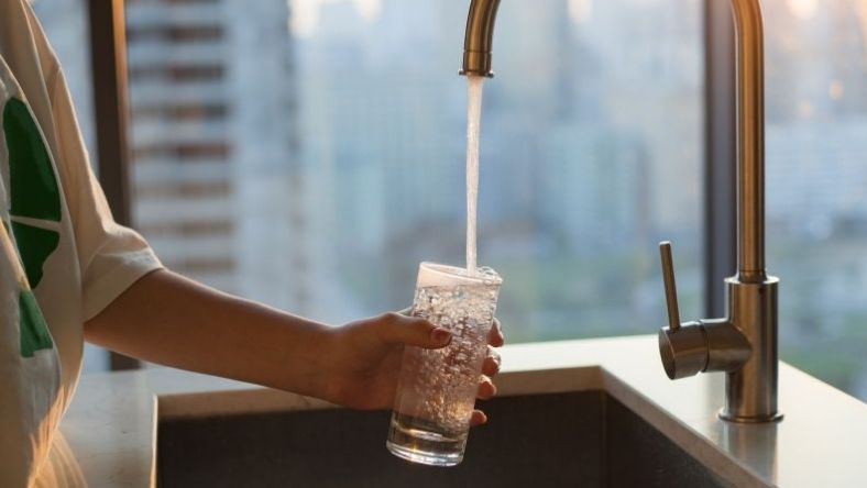 Glass being filled with tap water from kitchen faucet